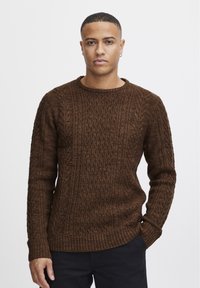 Pulover tricotat maro cu un model texturat, guler rotund și manșete cu nervuri. Material moale cu cabluri intricate pe corp și pe mâneci.