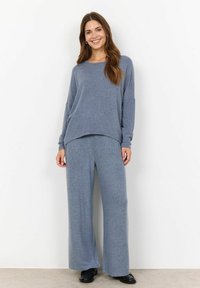 Ensemble de vêtements de détente bleu clair composé d'un haut à manches longues décontracté et d'un pantalon large en tissu doux et texturé avec un motif subtil.