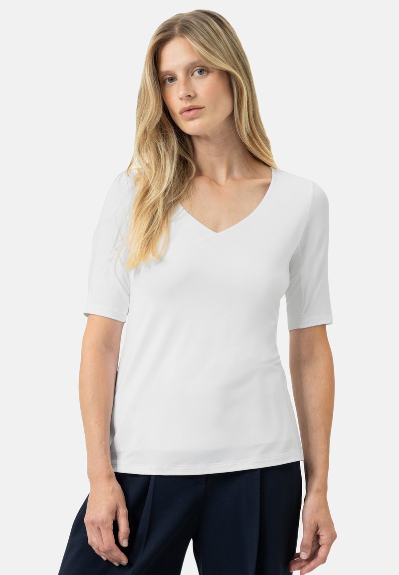 Witte V-hals T-shirt van glad, lichtgewicht materiaal met korte mouwen, getailleerd ontwerp en minimale details. Gecombineerd met marineblauwe broek.