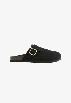 Sabots en suède noir avec une sangle réglable et un détail de boucle dorée. Doté d'une semelle texturée pour une bonne adhérence. Design simple et ouvert à l'arrière.