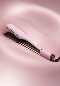 Prostownica do włosów o smukłej, różowej obudowie, czarnej ceramicznej płytce i złotych akcentach. Posiada teksturowany uchwyt oraz przyciski do regulacji temperatury.