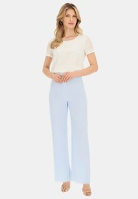 Jasnoniebieskie spodnie wide-leg połączone z dopasowaną, białą bluzką z krótkim rękawem. Gładka tekstura materiału z czystym, minimalistycznym wzornictwem.