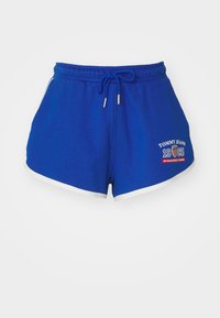 Modré bavlněné šortky se stahovací šňůrkou v pase, bílými bočními akcenty a potištěným logem. Mají uvolněný střih a jemnou texturu.