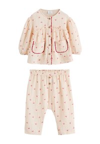 Ensemble deux pièces couleur pêche clair comprenant un haut boutonné à imprimé cerises et manches bouffantes, assorti d'un pantalon à taille élastique. Accents rouges.