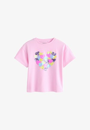 Rózsaszín pamut póló, amely szív alakú mintával rendelkezik, amely több színű flitterekből áll: sárga, lila, kék és zöld. Rövid ujjú és kerek nyakú.