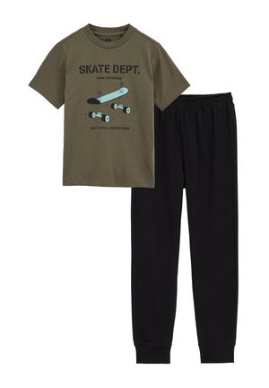 Kortærmet olivengrøn T-shirt med skateboardgrafik og sorte joggingbukser med elastisk talje.