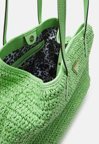 Zelená tkaná kabelka s koženými detaily, dvojitými ramenními popruhy, klopou na zacvaknutí a podšívkou z látky s leopardím vzorem, která obsahuje vnitřní kapsu na zip.