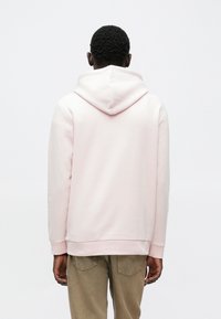 Hellrosa Kapuzenpullover mit großer, runder Kapuze, gerippten Bündchen und Saum. Der Stoff wirkt weich und glatt, ohne sichtbare Muster oder Logos.