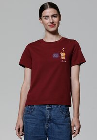 Bordeauxfarbenes Baumwoll-T-Shirt mit kurzen Ärmeln, das ein gedrucktes Grafikdesign eines Cartoon-Charakters zeigt, der ein Getränk hält, und den Text "Houston, wir haben ein Problem".