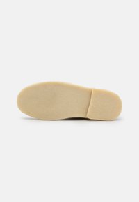 Light tan shoe sole with a smooth texture, rounded shape, and minimal tread pattern, designed for comfort and durability.
