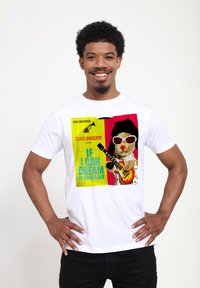 Hvid t-shirt med farverig grafik, der viser en tegneseriefigur med guitar, solbriller og tekst i livlige farver.
