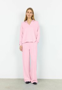 Svetloružová súprava na voľný čas s košeľovým vrškom s golierom a véčkovým výstrihom, dlhými rukávmi a širokými nohavicami, s jemnou textúrou a minimálnymi švami.