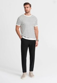 Wit en marineblauw gestreepte t-shirt met korte mouwen, gecombineerd met zwarte tapered broek en lichtbeige sneakers. Eenvoudig ontwerp, casual outfit.
