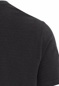 Schwarzes T-Shirt mit kurzen Ärmeln und einem strukturierten, gerippten Muster auf dem Stoff. Mit rundem Halsausschnitt und genähten Saumdetails.