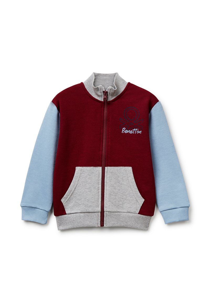 Chaqueta con cremallera en rojo y azul claro con detalles en gris. Cuenta con un cuello alto, dos bolsillos frontales y un logo bordado en el pecho.