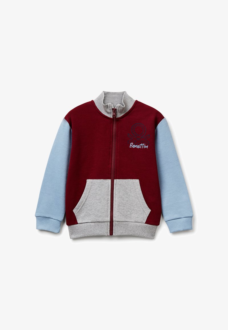 Chaqueta con cremallera en rojo y azul claro con detalles en gris. Cuenta con un cuello alto, dos bolsillos frontales y un logo bordado en el pecho.