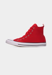 Κόκκινο ψηλό καμβαδένιο αθλητικό παπούτσι με λευκή λαστιχένια σόλα, λεπτομέρεια μαύρης ρίγας, λευκή μύτη και κόκκινες κορδόνια πάνω σε ανοιχτό γκρι φόντο.