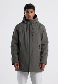 Giacca impermeabile grigia con cappuccio, zip frontale e cordini regolabili. Presenta una tasca con zip sul petto e due tasche laterali.