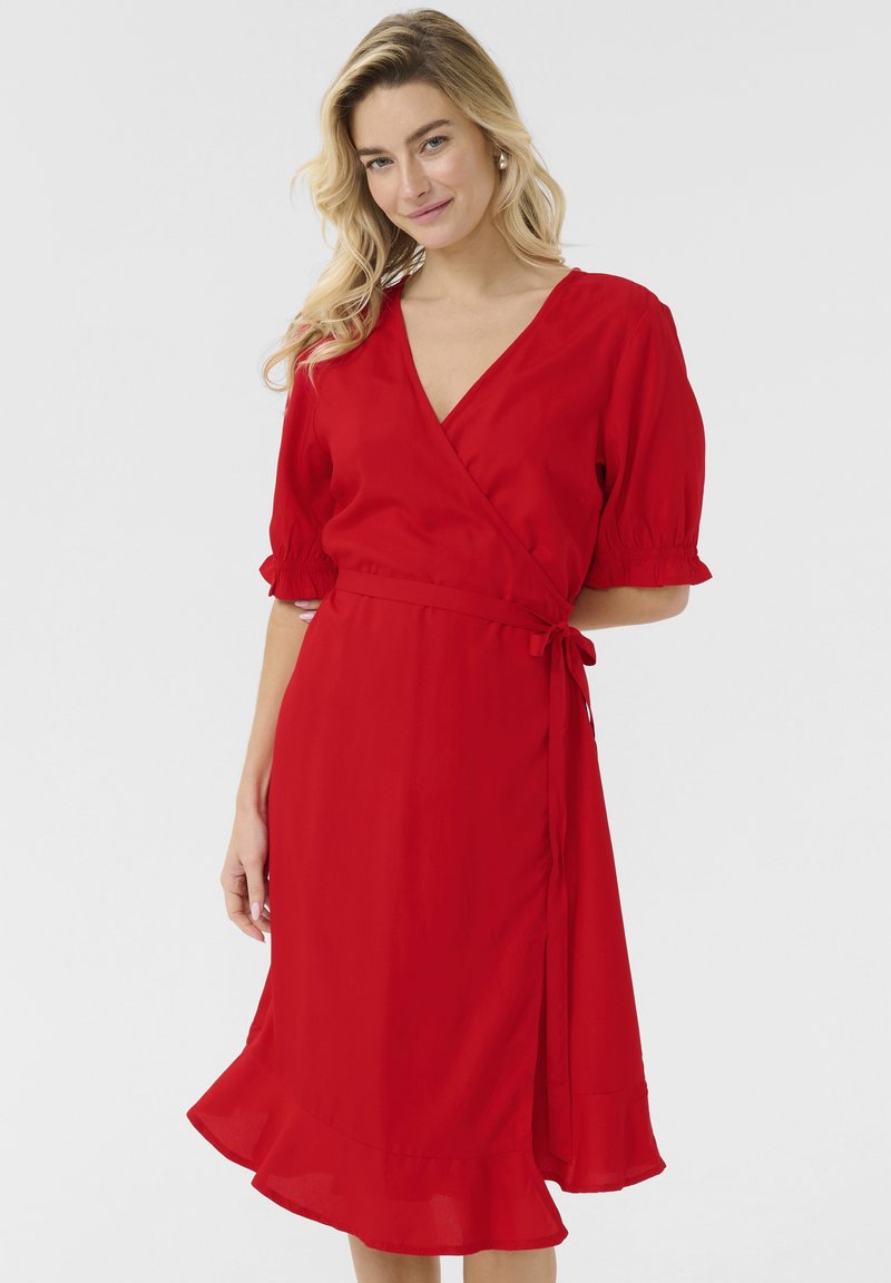 Robe enveloppante rouge avec des manches courtes bouffantes, un décolleté en V et un ourlet évasé. Fabriquée en tissu léger avec une texture lisse. Ceinturée.