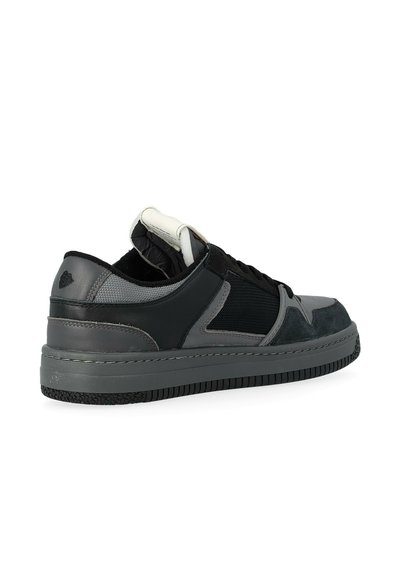 Sneaker a basso profilo in nero e grigio con suola testurizzata, linguetta imbottita e pannelli laterali in rete, mostrato da un'angolazione laterale posteriore su sfondo bianco.