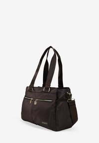 Bolsa tote de nylon marrón con dos asas superiores, correa ajustable, dos bolsillos frontales con cremallera y un parche de logo. Textura suave y diseño estructurado.