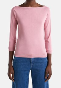 Pink knitted shirt with a wide boat neckline and three-quarter sleeves. Ribbed cuffs and hem, paired with blue wide-leg jeans.