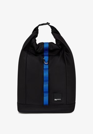 Juodas ritininis kuprinės modelis su vertikalia mėlyna juosta ir metaliniu sagtimi, turintis mažą stačiakampio formos logotipo etiketę arti apačios.