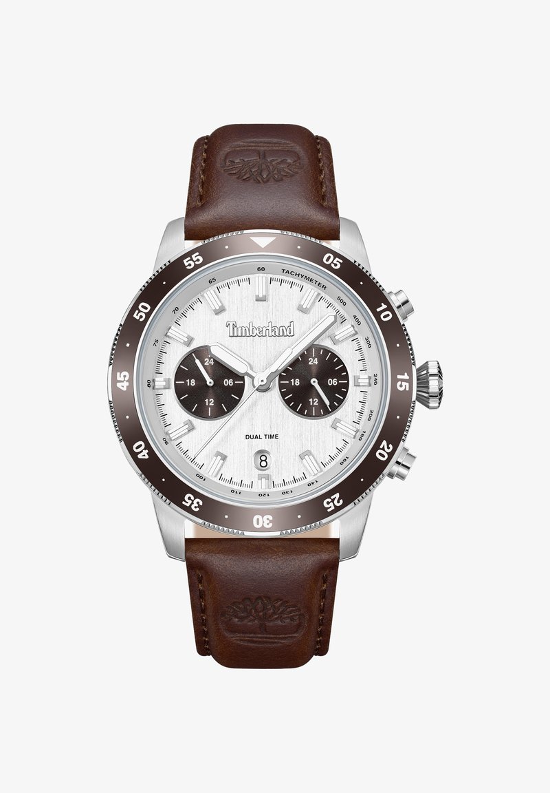 Montre-bracelet Timberland à double fuseau horaire avec cadran argenté, lunette marron, deux sous-cadrans, fenêtre pour la date, et bracelet en cuir marron embossé avec le logo arbre.