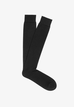 Calze nere fino al ginocchio realizzate in tessuto liscio ed elastico con polsino a costine in cima; senza motivi o decorazioni visibili.