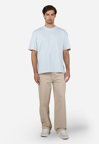 Light blue short-sleeve t-shirt paired with beige pants and light sneakers. The t-shirt has a relaxed fit and soft fabric.