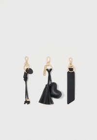 Τρία μαύρα αξεσουάρ κλειδιών: ένα πλεγμένο δερμάτινο, ένα κρόσσι με γοητεία σε σχήμα καρδιάς και μια επίπεδη δερμάτινη λωρίδα, όλα με χρυσά μεταλλικά αξεσουάρ.