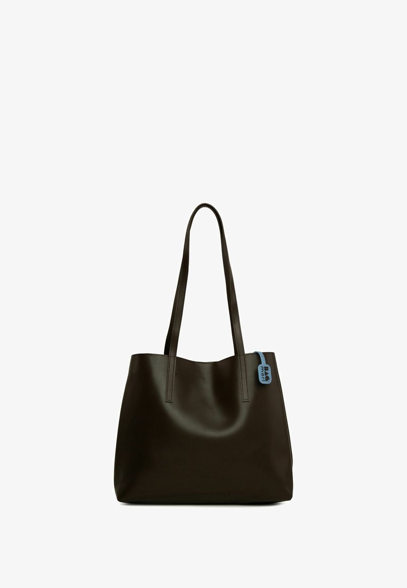 Geantă tote de culoare maro închis, cu două mânere lungi, din material sintetic neted, cu o formă rotundă și un accent de etichetă albastră pe o parte.