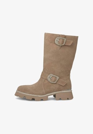 Stivale al ginocchio in suede marrone con una fibbia decorativa e dettagli in strass, suola in gomma texturizzata e tacco spesso.