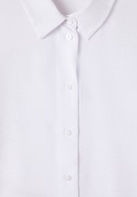 Camicia bianca a maniche lunghe con fibra testurizzata, colletto classico e cinque bottoni abbinati sul davanti. Design morbido e leggero.
