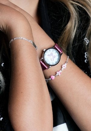 Montre avec un cadran blanc décoré d'un motif de papillon, bracelet en cuir rose et un bracelet en argent avec des perles roses et des accents floraux.