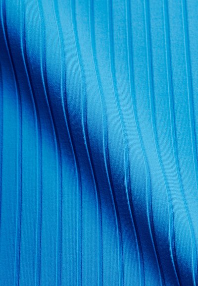 Tissu bleu avec une texture côtelée verticale et des ombres subtiles mettant en valeur le motif ondulé du matériau.