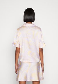 Kortärmad skjorta och matchande kjol i silkesliknande tyg, med ett lavendel- och gräddfärgat marmormönster, avslappnad passform och krage.