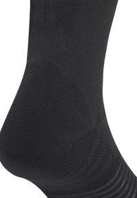 Musta sukka, jossa on ribbaustekstuuri, vahvistettu kantapää ja pehmustettu pohja. Suunnittelussa keskitytään mukavuuteen ja kestävyteen, ja pinta on sileä.