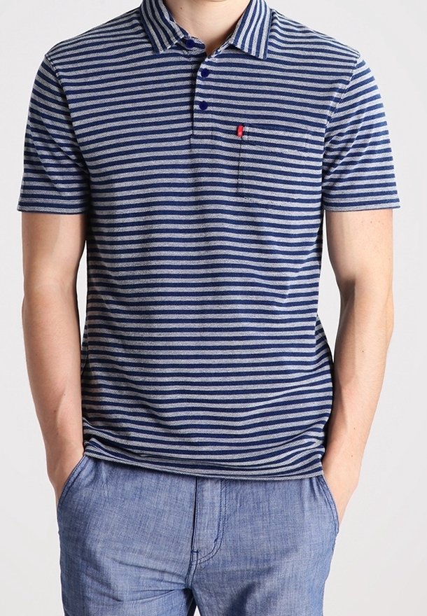 Homme portant un polo à rayures horizontales bleu et gris à manches courtes, avec col et poche poitrine, assorti à un pantalon décontracté bleu clair.