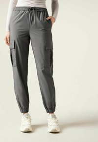 Graue Cargo-Hosen mit einem elastischen Bund, seitlichen Taschen und elastischen Bündchen. Aus glattem, leichtem Stoff gefertigt.