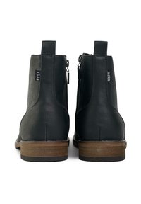 Black vegan ankle boots with a smooth faux leather finish, side zippers, and brown wooden heels. Features a minimalist design with no embellishments.