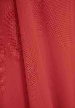 Czerwona siateczkowa tkanina posiada drobny, teksturowany wzór z małymi otworami, układając się miękko i mając lekki wygląd.