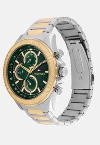 Silber- und goldfarbene Uhr mit einem grünen strukturierten Zifferblatt, drei Unterzifferblättern, goldenen Zeigern und einem Armband aus rostfreiem Stahl. Markenlogo angezeigt.