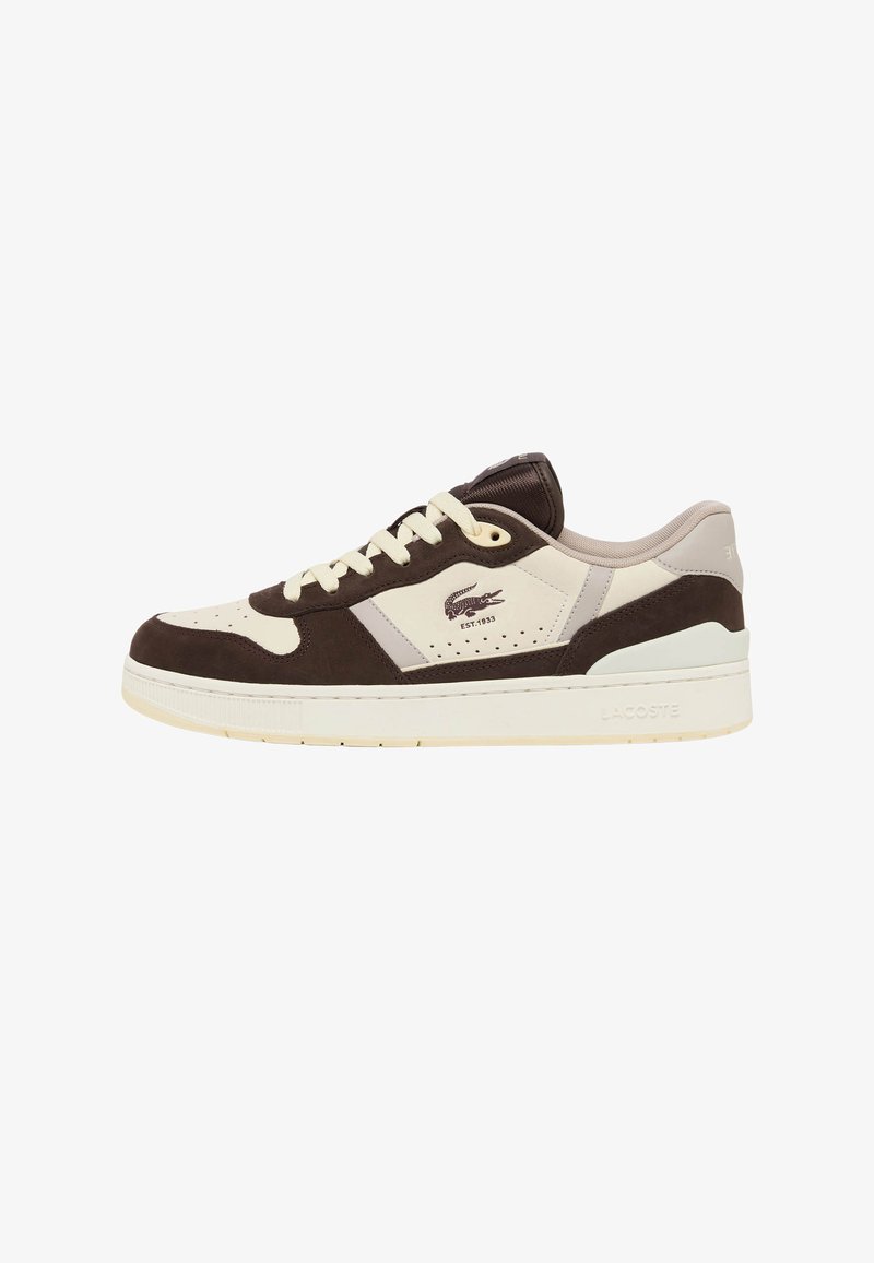 Baskets basses avec panneaux marron et beige, lacets blancs, bout perforé, et logo Lacoste avec "EST. 1933" sur le côté.