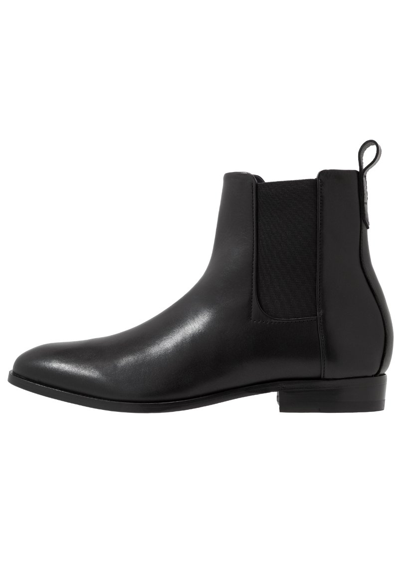 Botte Chelsea en cuir noir avec panneaux latéraux élastiques, bout arrondi et petit talon empilé. Texture lisse et design épuré.