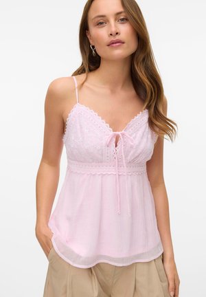 Camisole rose clair avec bretelles réglables, bordure en dentelle, avant à nouer, et tissu doux et fluide. Présente des détails en broderie anglaise sur le buste.