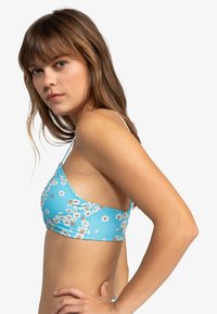 Lyseblå blomsterbralette med tynne stropper, med hvite og brune blomster mønster. Glatt stoff med en tettsittende design.