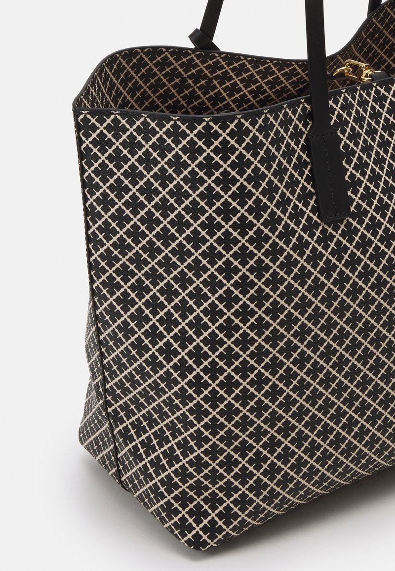 Black and cream tote bag made of textured material, featuring a diamond pattern, black straps, and a spacious interior.
