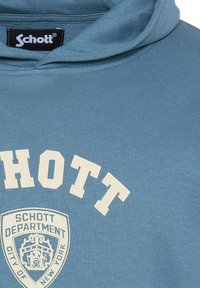 Sudadera con capucha azul hecha de tela acanalada que presenta un texto en blanco que dice "SCHOTT DEPARTMENT CITY OF NEW YORK" y una insignia de logo.