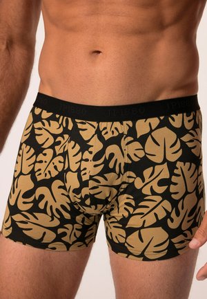 Zwarte boxershorts met een tropisch bladerenpatroon in goud, gemaakt van zachte stof met een elastische zwarte tailleband waarop de merknaam staat.